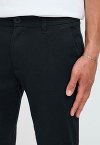Zwarte katoenmix broek met een soepele textuur, slim fit en zijzakken, met een knoopsluiting bij de taille.