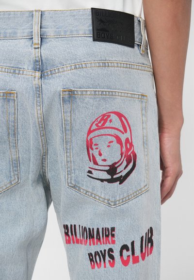 Šviesiai mėlynos džinsinės kelnės su juodu odiniu ženkleliu, ant užpakalinio kišenės su raudonu astronauto grafiką ir užrašu "BILLIONAIRE BOYS CLUB".