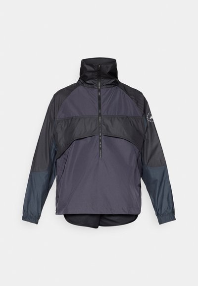 Αντιανεμικό μπουφάν σε σκούρο γκρι και μαύρο. Διαθέτει ψηλό γιακά, μισό φερμουάρ μπροστά και ελαστικούς καρπούς. Σχέδιο πάνελ με ποικιλία υφών.