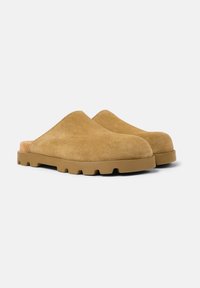 Muler i mjuk tan mocka med rund tådesign. Tjock gummisula med texturerad yta för bra grepp. Slip-on stil utan bakstöd.