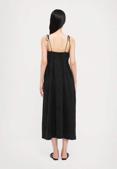 Schwarzes Midi-Kleid mit dünnen verstellbaren Trägern, strukturiertem Stoff und gerafftem Oberteil. Es zeichnet sich durch eine lässige Silhouette und eine Länge unterhalb des Knies aus.