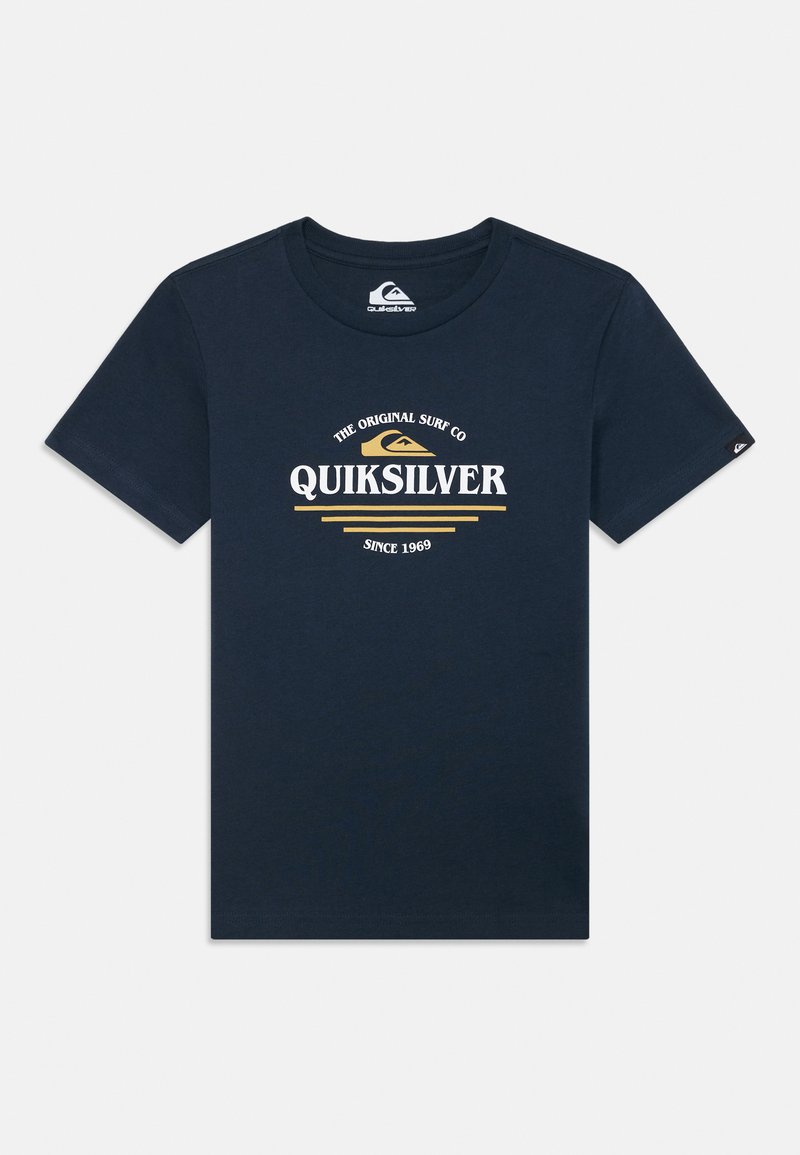 Camiseta de algodón azul marino de manga corta. En el frente presenta el logotipo "Quiksilver" en blanco y dorado, con texto curvado y líneas decorativas.