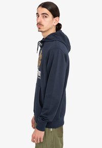 Dunkelblaues Hoodie aus weichem Material mit einer vorderen Tasche, einem Kordelzug-Kapuze und einem grafischen Design in Gold und Weiß auf der Brust.