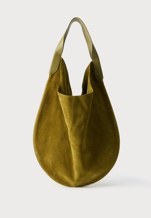 Sac hobo en daim vert olive avec une large bandoulière en cuir et une forme souple et arrondie sur un fond clair uni.