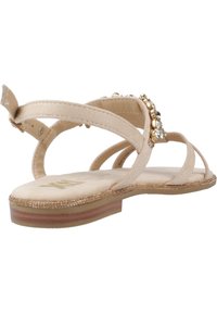 Sandalias planas beige con múltiples correas, adornadas con piedras de strass doradas y transparentes, que cuentan con una plantilla acolchada y una suela texturizada.