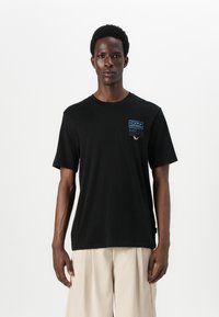 Black cotton t-shirt with short sleeves, featuring a blue logo on the left chest. Simple, relaxed fit and classic round neckline.