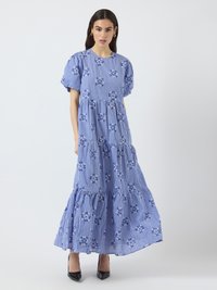 Maxiklänning i blått rutmönster med blommönster. Har puffärmar, en lagerdesign och en svängig kjol. Buren med svarta klackar.
