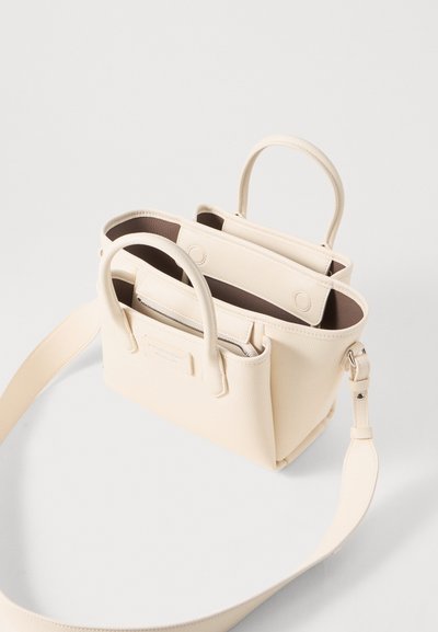 Bolso de mano en imitación cuero crema con duales asas cortas, un strap ajustable para el hombro y dos compartimentos. Textura suave y diseño minimalista.
