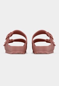 Ζευγάρι ματ ροζ σανδάλια με διπλά ρυθμιζόμενα λουριά και υφασμένα πέλματα, φωτoγραφημένα από πίσω σε λευκό απλό φόντο.