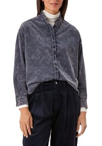 Camicia button-up blu carbone con colletto arricciato, maniche lunghe e vestibilità rilassata, abbinata a pantaloni in velluto a coste blu navy con texture rigata.