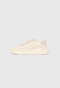 Smėlio spalvos sportiniai batai su lygiu oda ir zomšos tekstūromis, turintys ryškų logotipą, apvalų pirštą ir paminkštintą pado dalį.