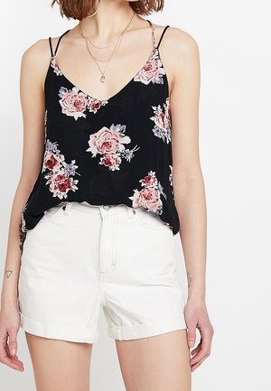 Débardeur noir à motifs floraux roses et bleus, avec des bretelles fines et une coupe fluide, associé à un short en denim blanc.