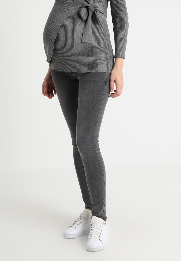 Sweater gris con textura acanalada y detalle de nudo combinado con jeans skinny gris y zapatillas blancas. Textura suave, diseño ajustado y estilo informal.