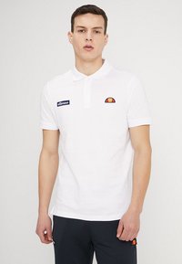 Weißes Poloshirt mit kurzen Ärmeln, Kragen und gesticktem Logo auf der Brust. Der Stoff sieht glatt aus und hat ein kontrastierendes Logo in Rot und Gelb.