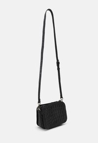 Borsa a tracolla nera con finitura texture, dotata di una lunga tracolla regolabile e chiusura con zip, posizionata su uno sfondo bianco.