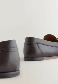 Brune læder loafers med en glat overflade, lav profil gummisål, minimalistisk design og diskret syning langs den øverste kant.