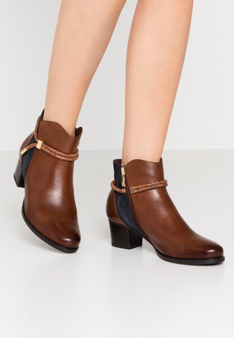 Bottes basses en cuir marron avec bout arrondi, fermeture éclair latérale et un détail tressé. Dotées d'un revers incurvé et d'un petit talon bloc.