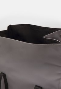 Szara torba na ramię o gładkim, matowym wykończeniu. Posiada czarne materiałowe uchwyty, szeroką otwartą górę oraz minimalistyczny design. Wnętrze ma zapięcie na rzep.