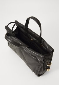 Black quilted leather tote bag with two handles, gold hardware accents, and a spacious interior. Visible stitching detail along the sides.