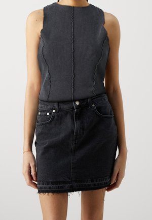 Schwarzes, geripptes Tanktop mit hohem Ausschnitt, kombiniert mit einem schwarzen Jeansrock mit ausgefranstem Saum und Fronttaschen.