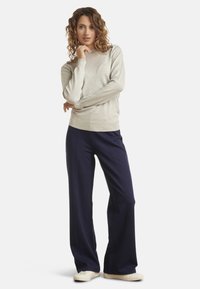 Light gray sweater with long sleeves, round neckline, and ribbed hem, paired with dark navy wide-leg trousers and white sneakers.