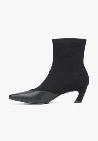 Czarne botki za kostkę z zamszu, o spiczastym nosku i niskim, zaokrąglonym obcasie; posiadają gładką skórzaną nasadkę na czubku.