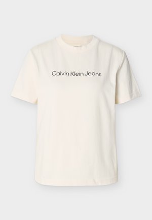 Bombažna majica kremaste barve s kratkimi rokavi in okroglim izrezom. Na prsih je črni napis "Calvin Klein Jeans".