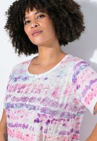 Kortærmet T-shirt i let stof, prydet med et blomsterdesign i pink, lilla og blå med nitter på fronten.