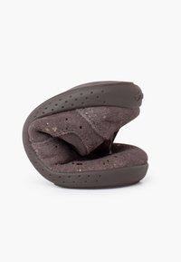 Scarpa pieghevole marrone con la parte superiore morbida simile a suede, forma arrotondata, suola in gomma perforata e design stratificato per comfort e flessibilità.