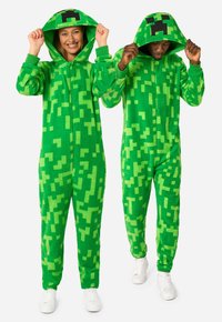 Green fleece onesies with pixelated patterns. Features a hood, front zipper, and ribbed cuffs. Worn by two individuals, one smiling.