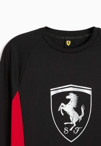 Cămașă neagră cu mâneci lungi și accente roșii, având un logo cu un scut argintiu, ce prezintă un cal în picioare și textul "SF". Fabricată dintr-un material neted.