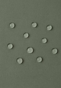 Tessuto texture in verde tenue con diverse gocce d'acqua trasparenti sulla superficie, creando un contrasto tra le gocce e lo sfondo.