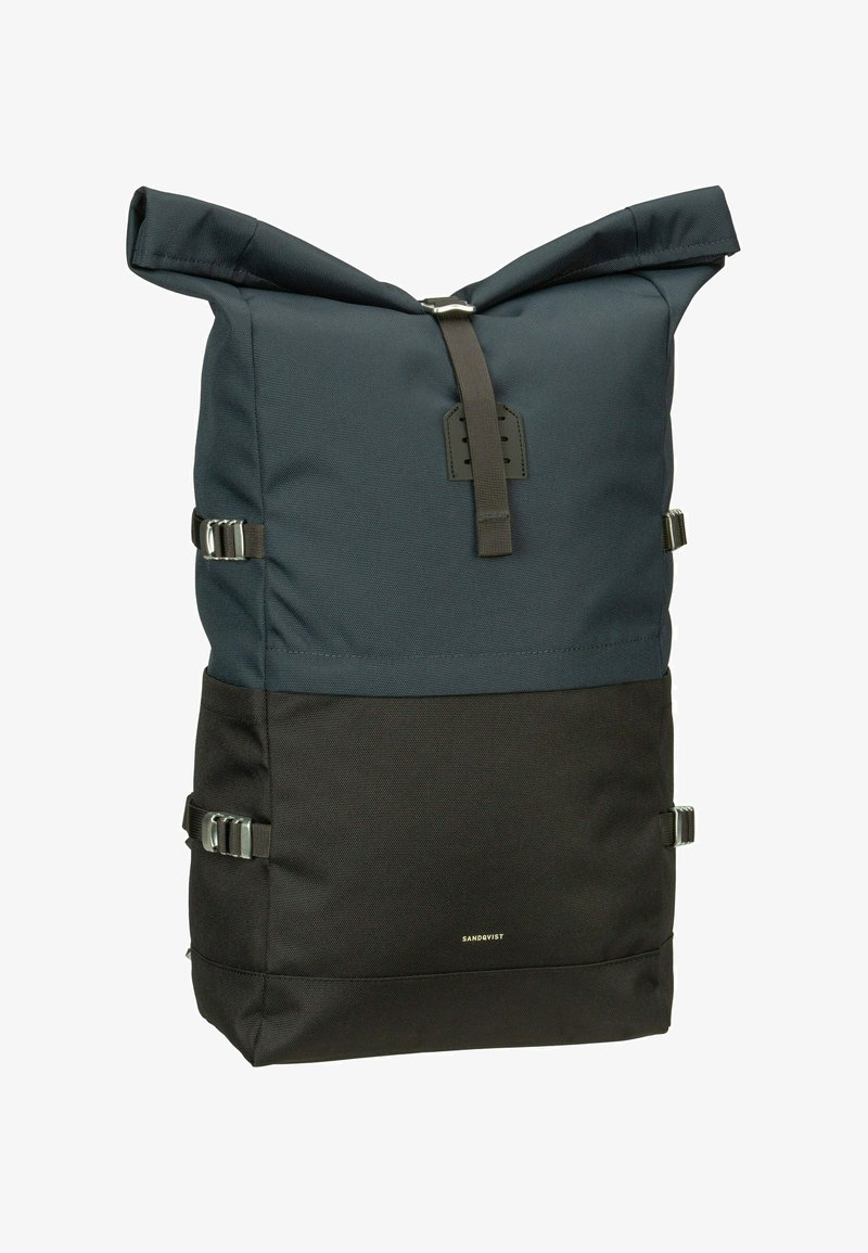 Mochila con cierre enrollable en tejido azul marino y negro, que cuenta con herrajes plateados, hebillas laterales y una superficie texturizada. Logotipo de la marca en la parte frontal.