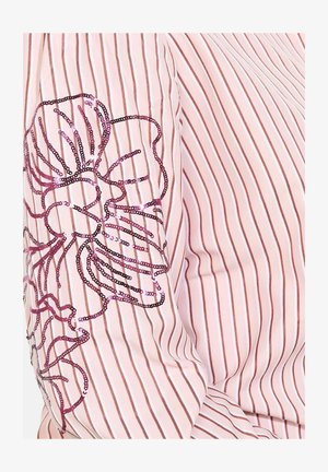 Bluse in hellrosa mit Streifen, die ein florales Design aus Pailletten in Rosa- und Schwarztönen auf dem linken Ärmel zeigt, aus strukturiertem Stoff.