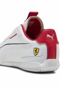 Valkoinen ja punainen lenkkari, jossa on teksturoitu yläosa, rei'itettyjä yksityiskohtia, Puma-logo ja Ferrarin vaakuna sivussa. Kumiulkopohja.