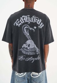 Sort bomuld T-shirt med et stort gråt grafisk motiv af en slange og kranie med teksten "Ed Hardy" og "Los Angeles" trykt på ryggen.