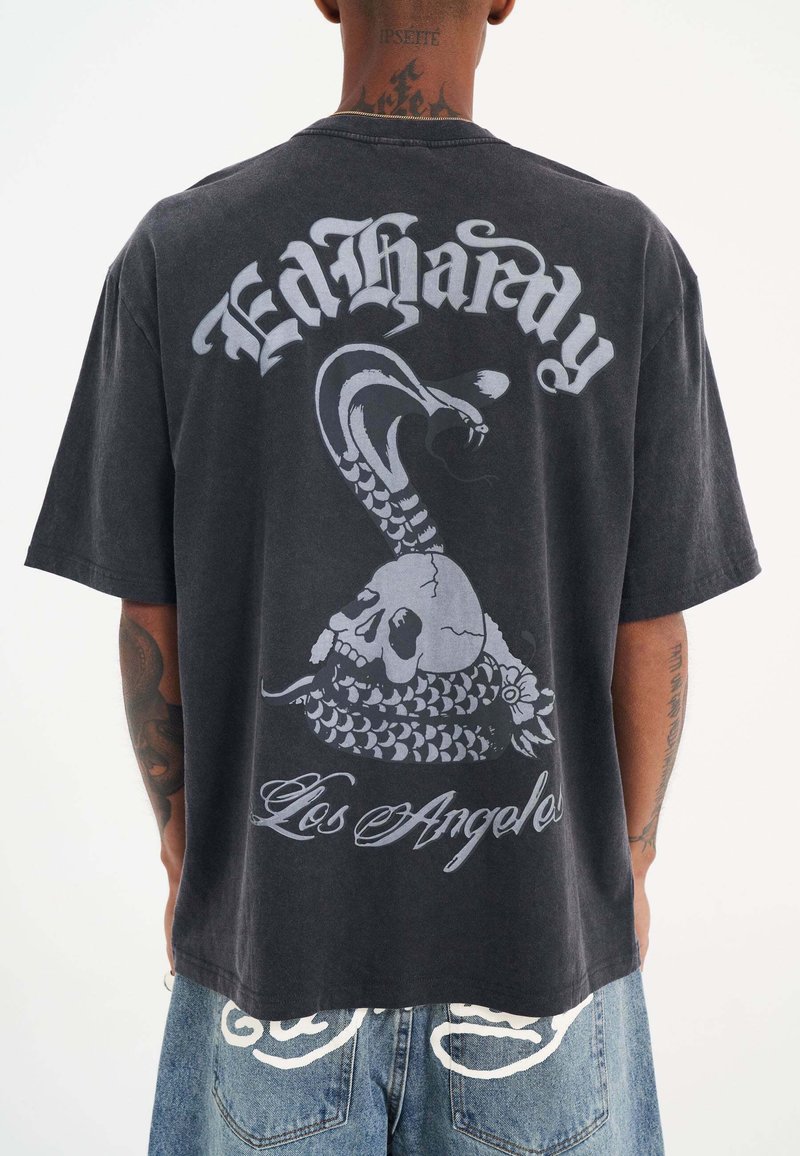 Sort bomuld T-shirt med et stort gråt grafisk motiv af en slange og kranie med teksten "Ed Hardy" og "Los Angeles" trykt på ryggen.