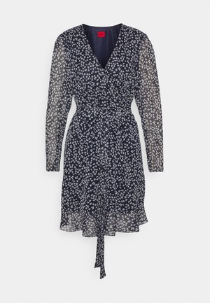 Robe portefeuille noire à manches longues avec petit imprimé floral blanc, col en V, manches transparentes et ceinture à nouer à la taille.