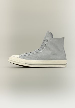Γκρι καμβαδένιο sneaker ψηλής κορυφής με λευκή λαστιχένια σόλα και άκρη δακτύλου, γκρι κορδόνια και υφασμάτινη υφή, εμφανίζεται σε πλάγια όψη σε ουδέτερο φόντο.