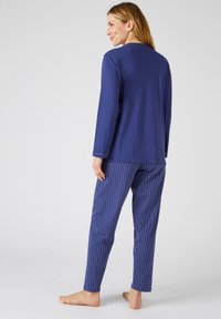 Ensemble de pyjama bleu marine avec un haut à manches longues et un pantalon à motif à pois ; tissu doux, coupe ample et détail de col simple.