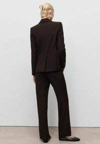 Brown tailored suit with a single-breasted jacket and straight-leg trousers. Smooth texture, minimalistic design, and hidden back vents.