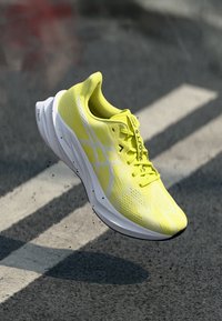 Lightweight running shoe in bright yellow mesh, featuring white accents, perforated textures, and a sleek design with a cushioned sole.
