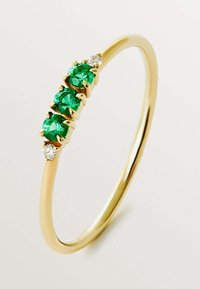 Anillo de oro que presenta tres piedras preciosas verdes y dos pequeños diamantes claros, con un acabado suave y pulido y un diseño minimalista.