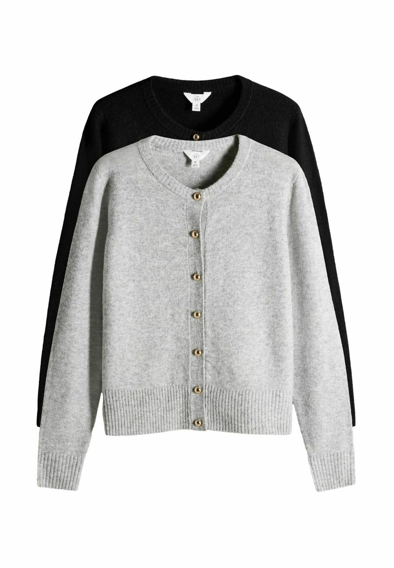 Dwa kardigany na wystawie: jasnoszary z przodu z złotymi guzikami, żebrowanym dołem, a czarny z tyłu. Oba mają okrągły dekolt.