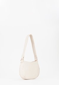 Sac à épaule en cuir beige avec une forme arrondie, orné de couture décorative le long du côté et d'une bandoulière plate et réglable.