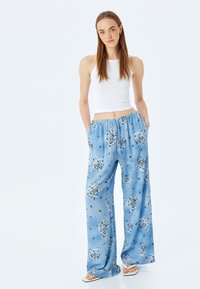 Pantalons à motif bleu clair avec une coupe décontractée, fabriqués à partir d'un tissu lisse. Dotés d'une taille élastique et de poches latérales, ornés de motifs paisley.