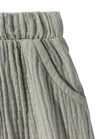 Světle šedá texturovaná látka s pomačkanym vzhledem, zahrnující elastický pas a detail boční kapsy.