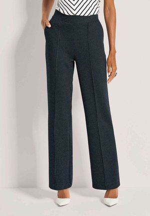 Wijd gesneden gestreepte broek in donkerblauw met een gestructureerde stof, voorzien van zijzakken en een gladde tailleband. Gecombineerd met witte hakken.