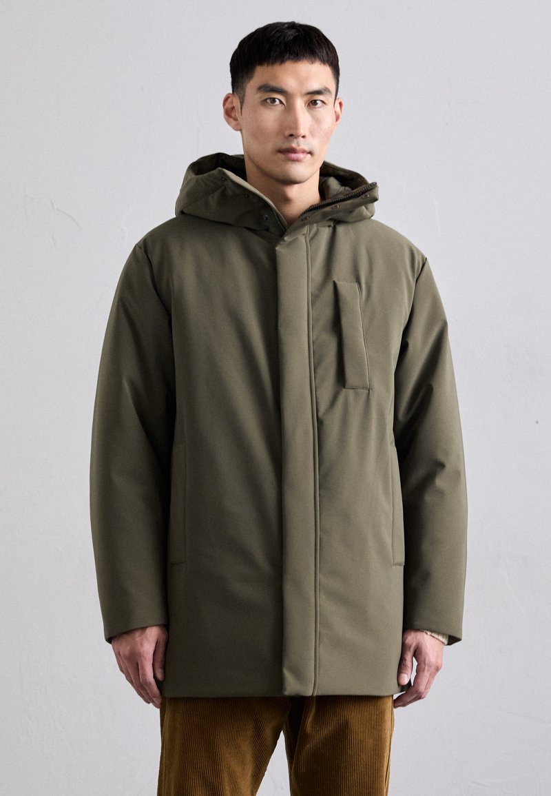 Cappotto isolato verde oliva con cappuccio, dotato di chiusura frontale e una tasca sul petto. Texture liscia e forma rettangolare moderna.