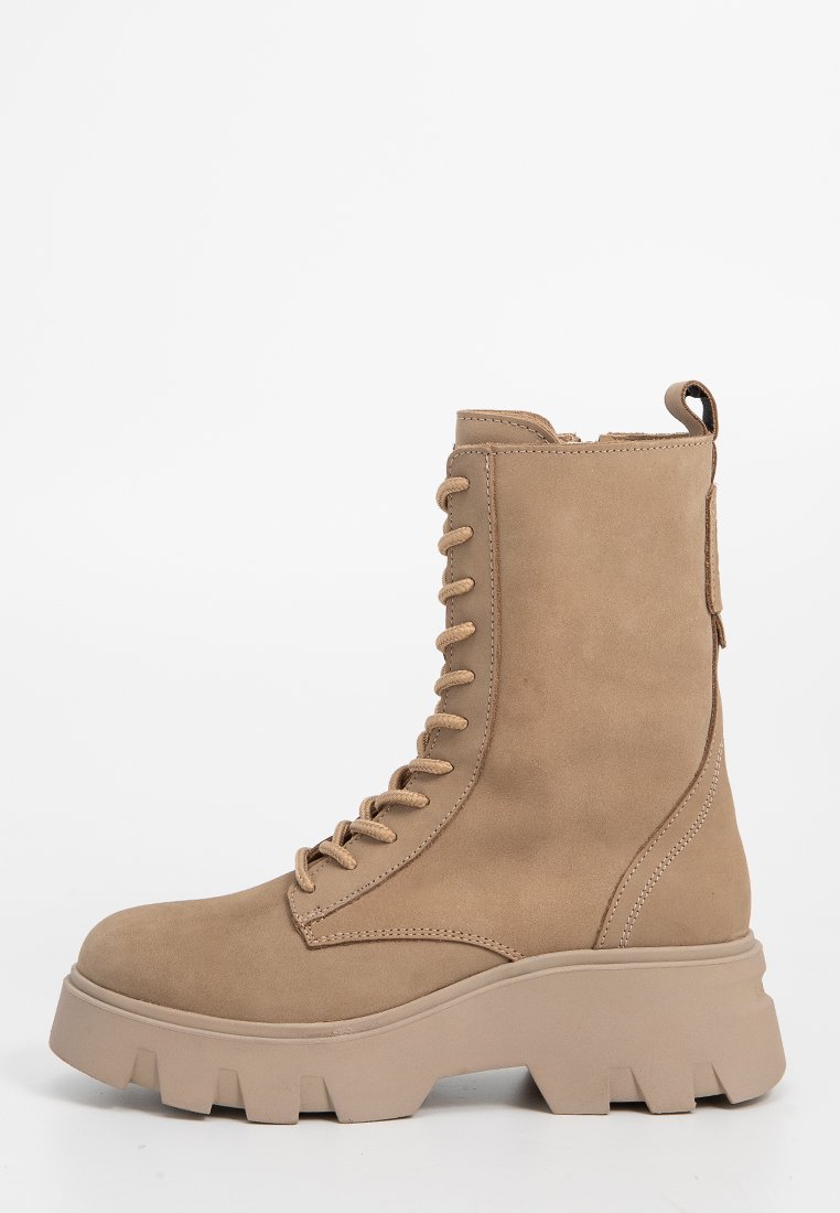 Beige Knöchelboot mit glatter Textur, Schnürung an der Vorderseite, dicker Sohle und gepolsterter Schuhkragen. Flacher Absatz mit einer Schlaufe für einfaches Anziehen.